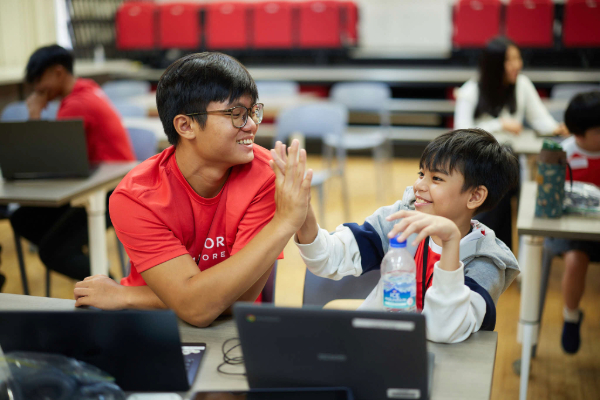 A volunteer and child giving each other a ‘high five’.
