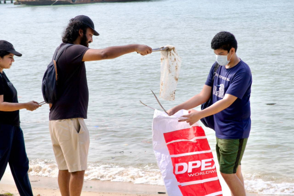 Two volunteers picking up trash at the beach.