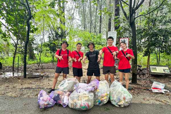 5 volunteers consolidating the trash they collected from a beach clean-up.
