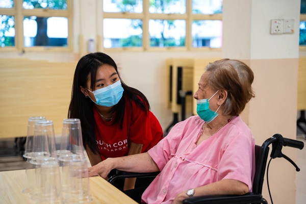 A volunteer befriending a senior sitting in a wheelchair.