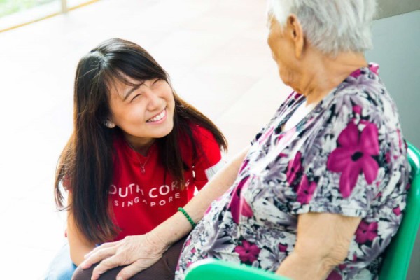 A volunteer smiling while interacting with a senior.