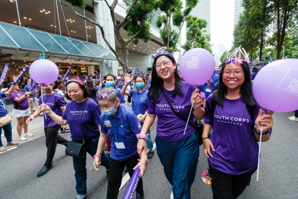 Volunteers marching at Purple Parade with person with special needs.