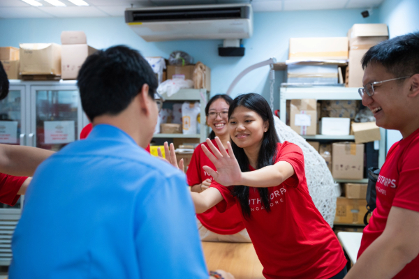 Three volunteers smiling and interacting with a person with special needs.